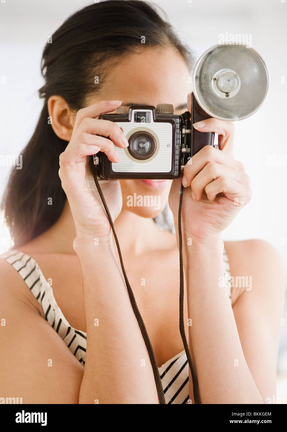 Mixed race woman using old-fashioned camera Stock Photo