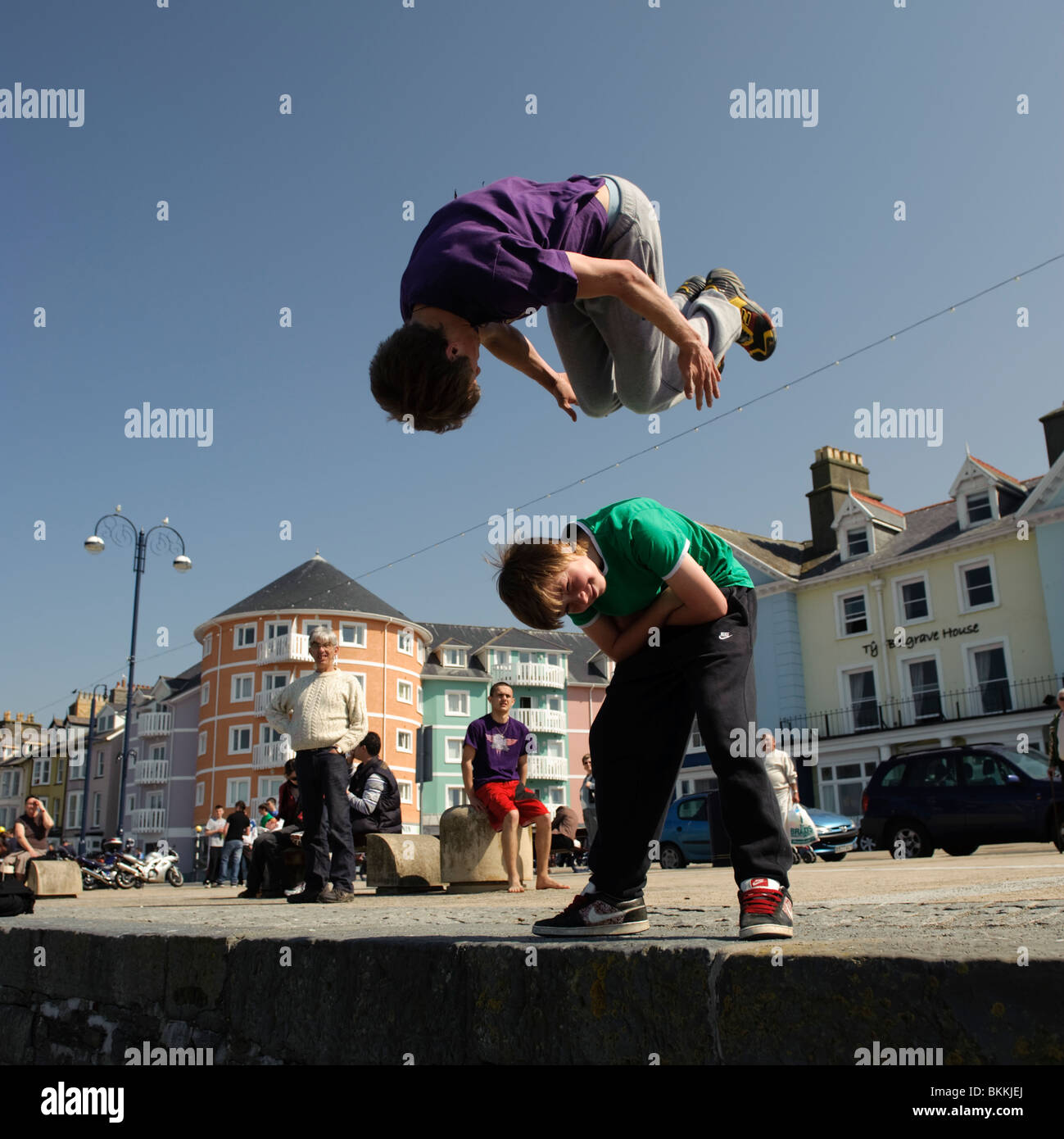 a young man practicing Freerunning parkour somersaulting over his friend on a sunny day Aberystwyth Wales UK Stock Photo
