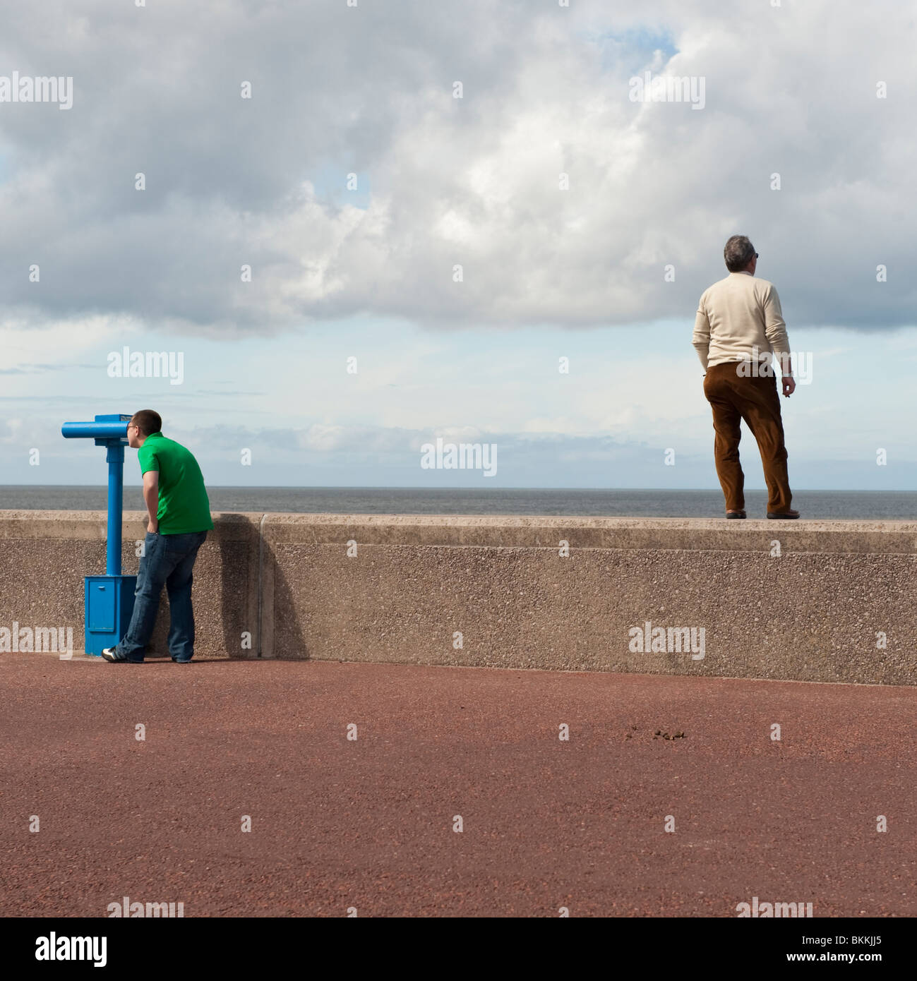 Rear view of a man standing on sea wall, another man looking through  telescope, Rhyl, north wales UK Stock Photo - Alamy