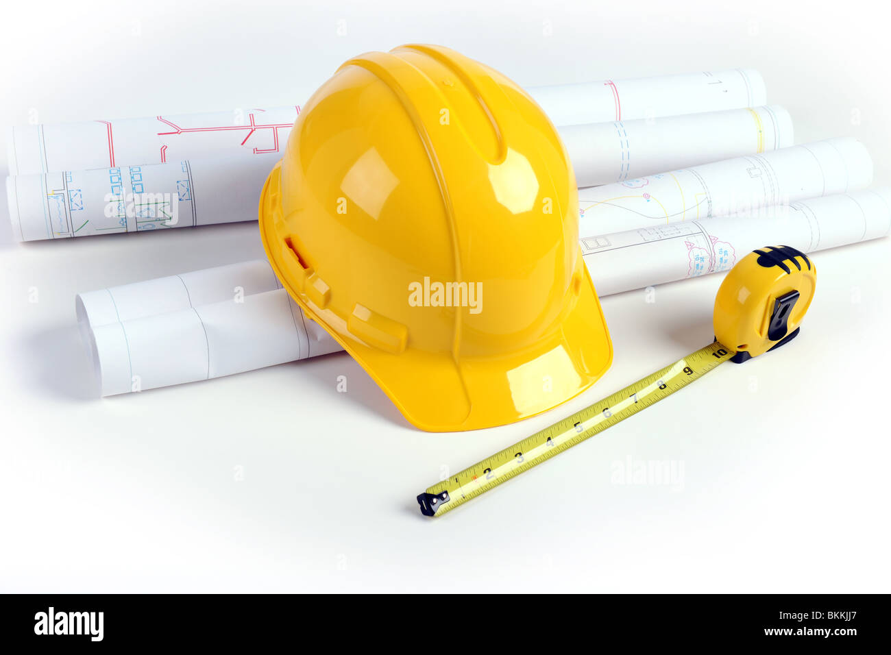 Architectural plans, hardhat and measuring tape over white table Stock Photo