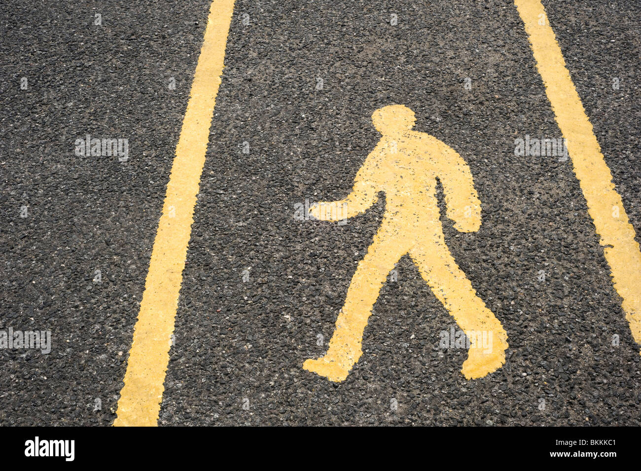 Yellow Pedestrian Walkway Sign painted on a Tarmac Road Surface in a Carpark Stock Photo
