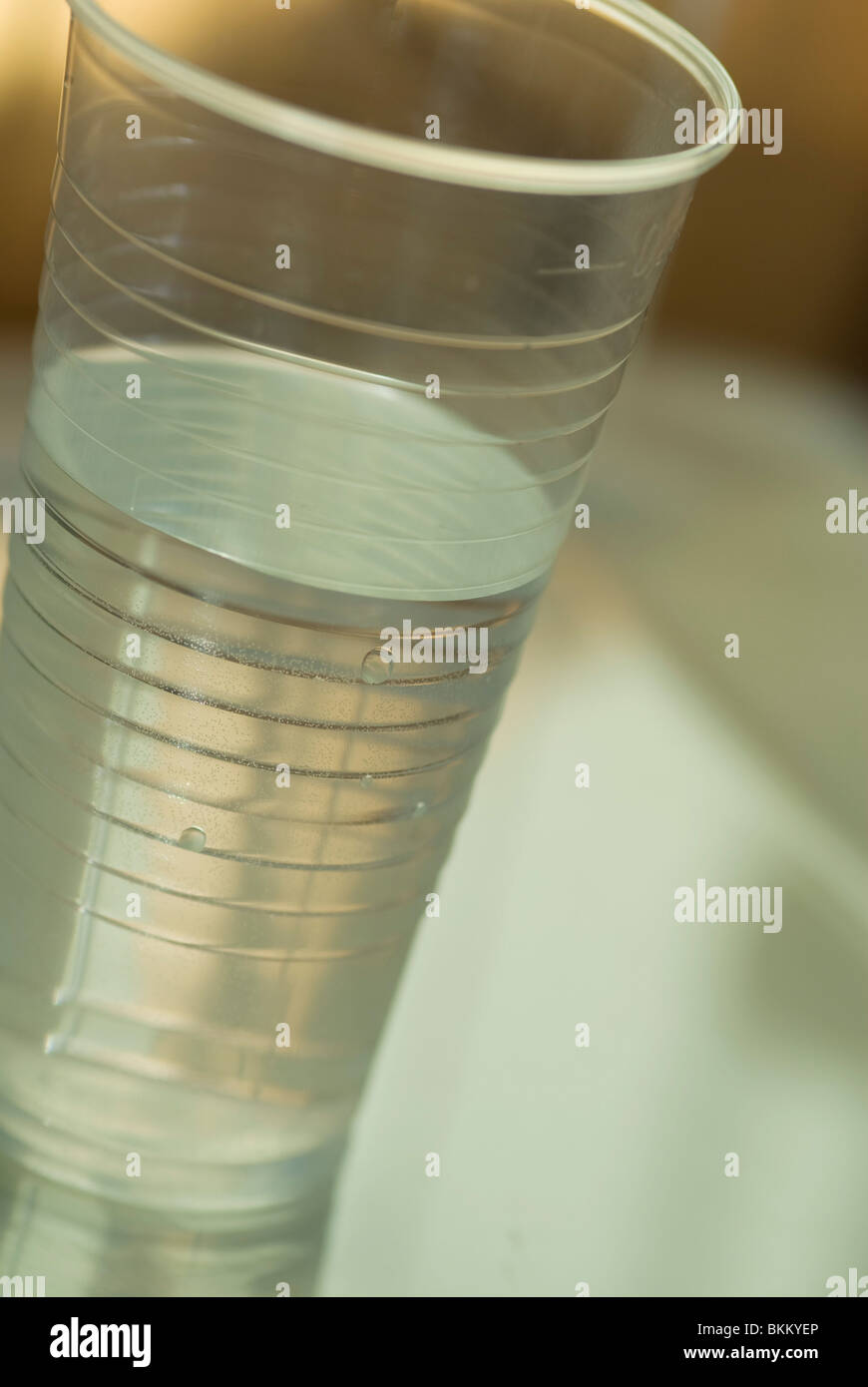 a plastic cup half filled with water set at an angle Stock Photo