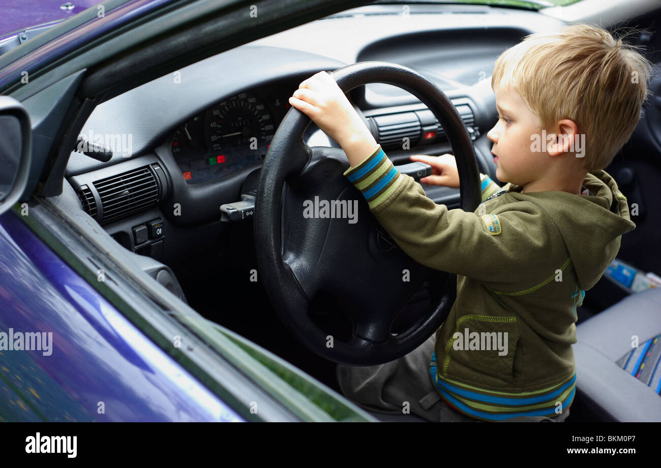 Child blond boy driving - playing real car Stock Photo