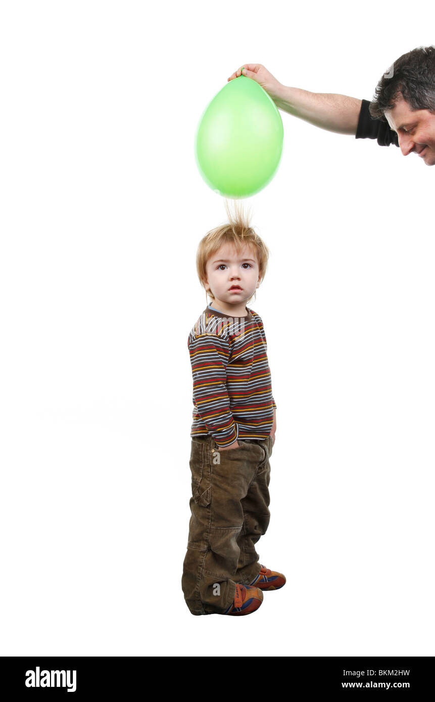 little boy's hair being attracted by an air balloon charged with static electricity Stock Photo
