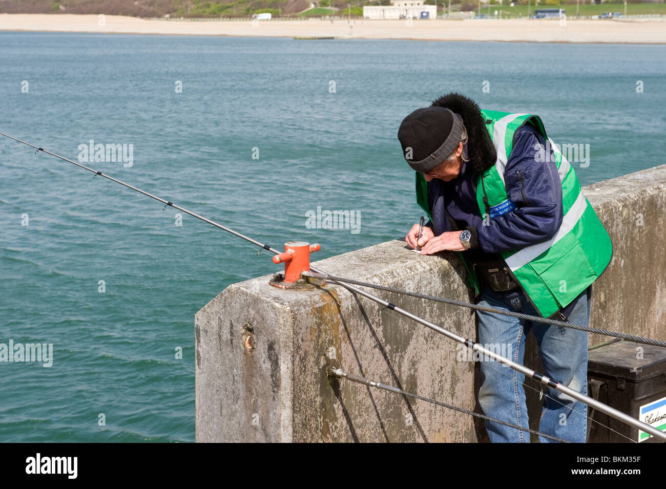 Sea angler and  fisherman fishing from the West arm of Brighton Marina Brighton Sussex UK Stock Photo