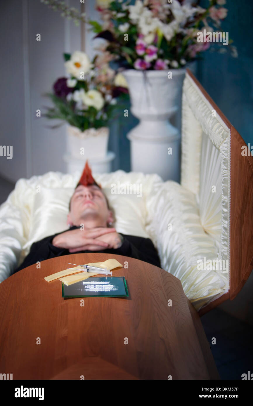 A Deceased Young Man In A Coffin With Syringes Laying On Top Stock Photo