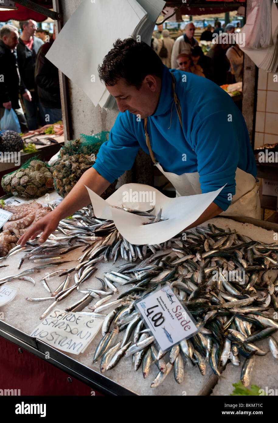Fishmonger selling sardines at fish market near Rialto Bridge in Venice