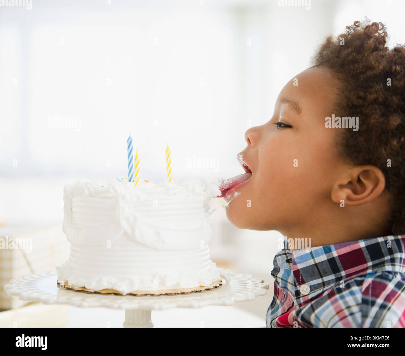 Black boy licking birthday cake Stock Photo