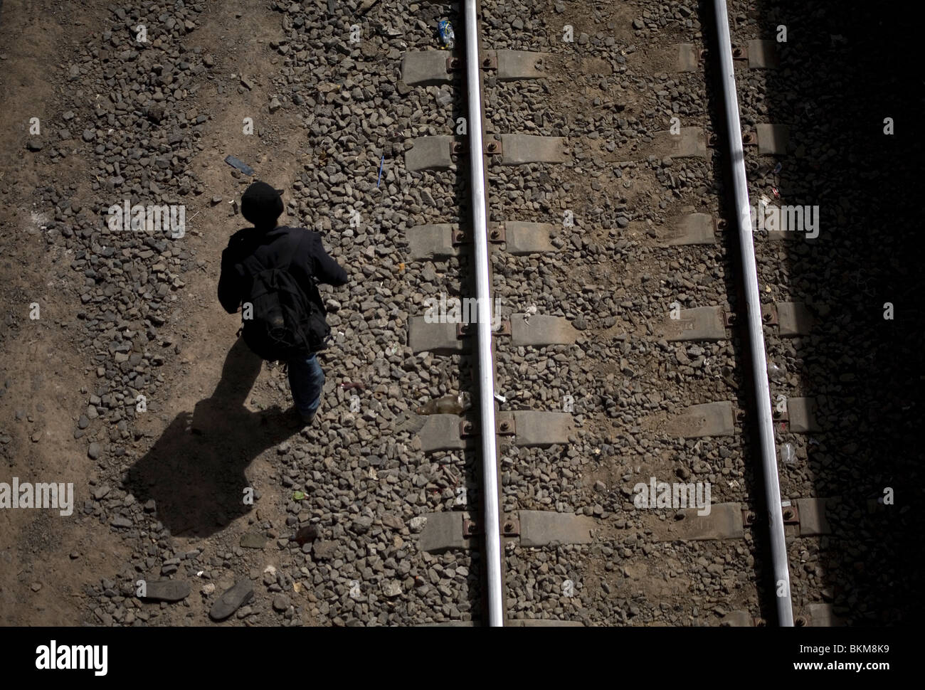 An undocumented Central American migrant traveling across Mexico to the United States walks along a railway track in Mexico City Stock Photo