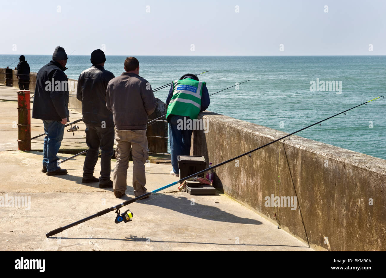 Sea anglers and  fishermen fishing from the West arm of Brighton Marina Brighton Sussex UK Stock Photo