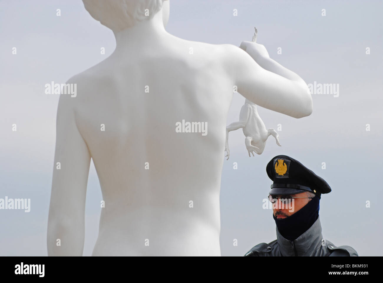 A policeman stands next to Charles Ray's 'Boy With Frog' at the Dogana, Venice, Italy Stock Photo