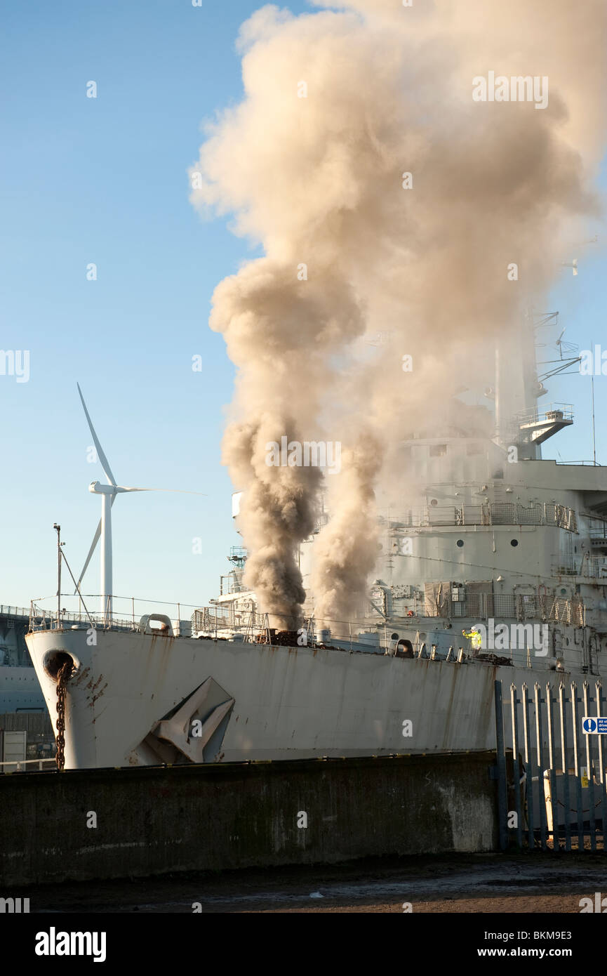 Ex Navy Ship on fire in dock with large volumes of smoke coming from hold Stock Photo