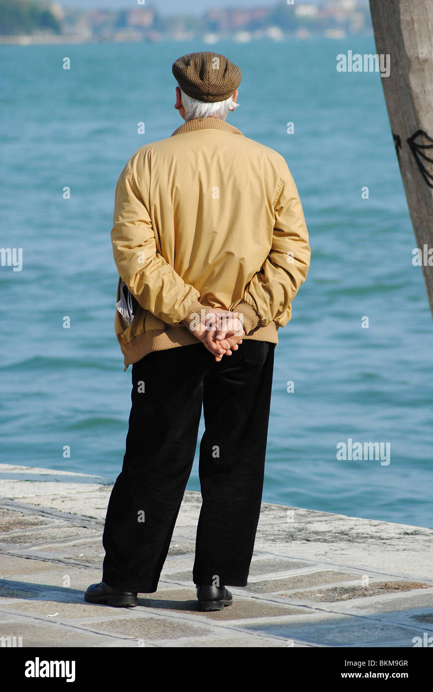 Old Italian man looking out to sea, Venice, Italy Stock Photo