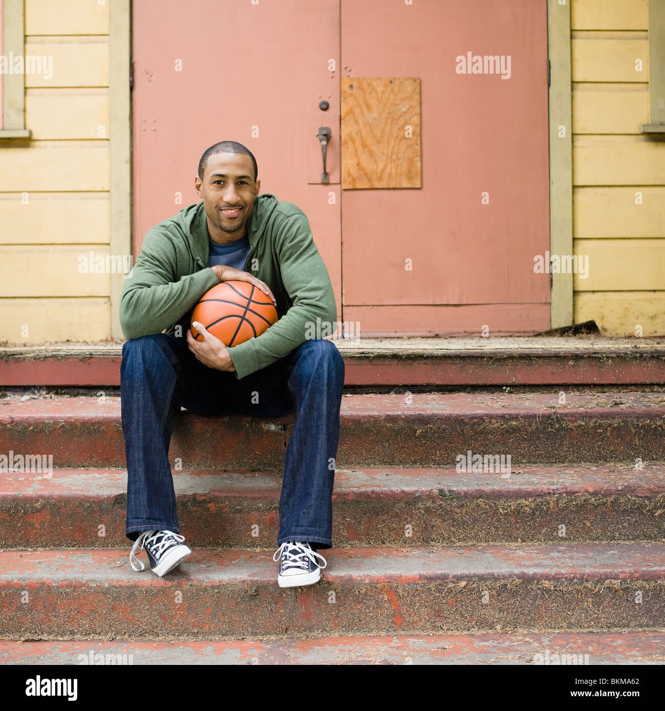 African American man sitting on steps with basketball Stock Photo