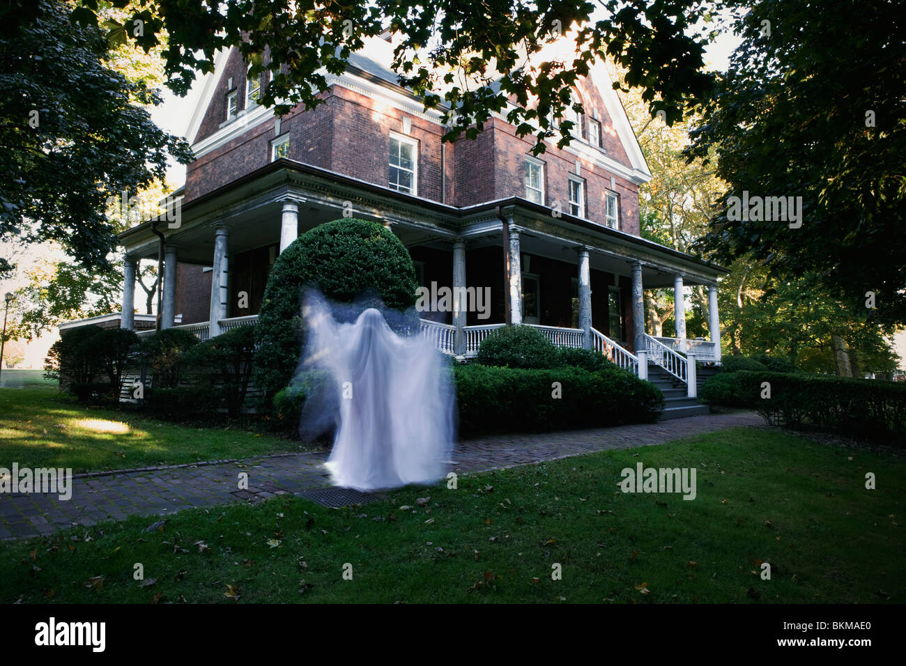 ghostly figure in front of house late afternoon Halloween scary sheet Stock Photo