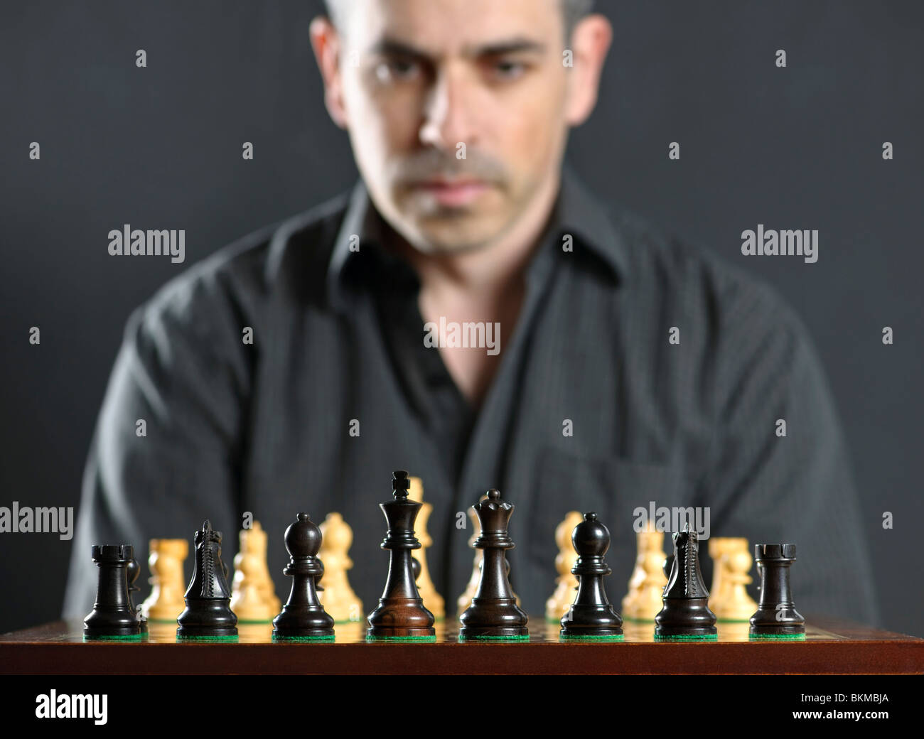 Man looking at wooden chess board thinking about first move Stock Photo