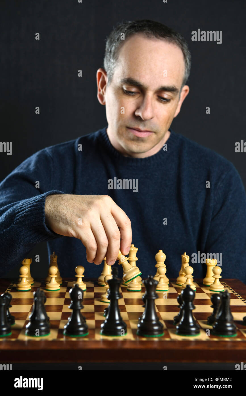 Man moving a chess piece on wooden chessboard Stock Photo