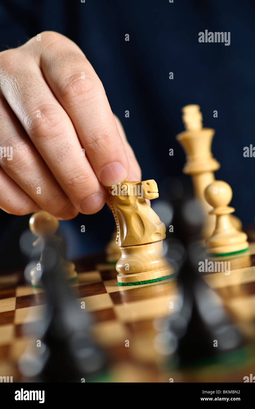 Hand moving a knight chess piece on wooden chessboard Stock Photo