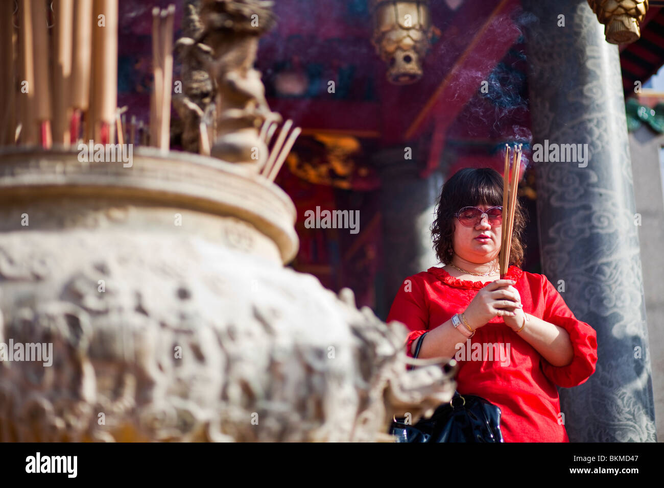 A woman makes an incense offering at the Tua Pek Kong Chinese Temple. Kuching, Sarawak, Borneo, Malaysia. Stock Photo