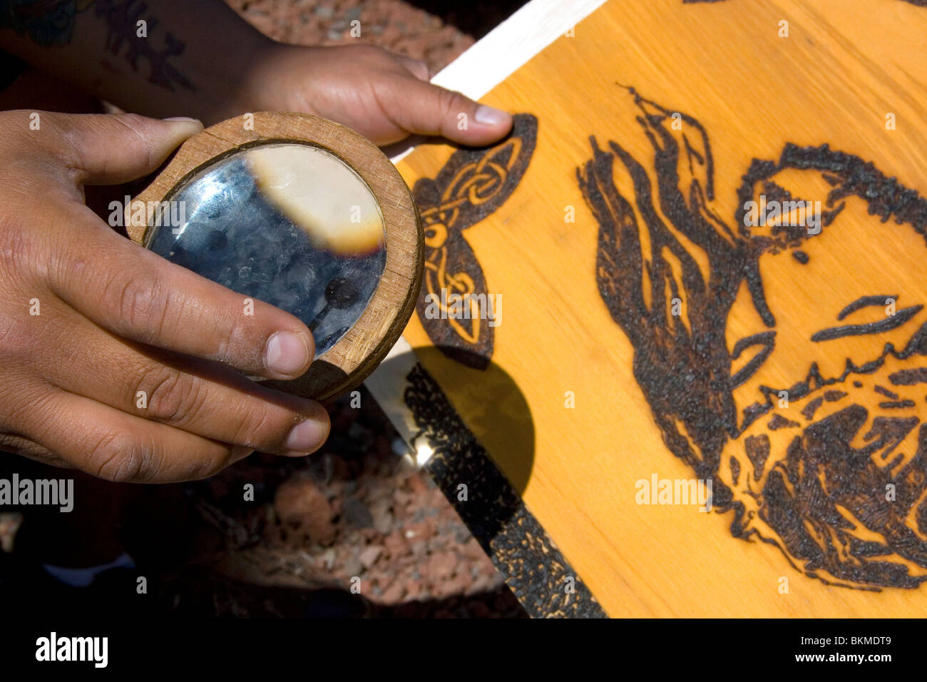 Sunlight being concentrated with a magnifying lens to burn a design into wood creating art. Cholula, Puebla, Mexico. Stock Photo