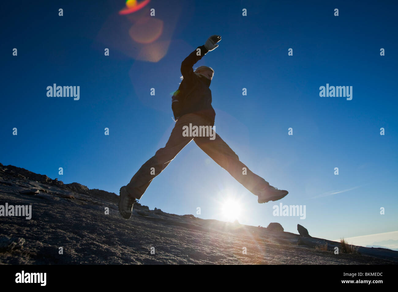 Woman leaping across rockface on Mt Kinabalu. Kinabalu National Park, Sabah, Borneo, Malaysia. Stock Photo