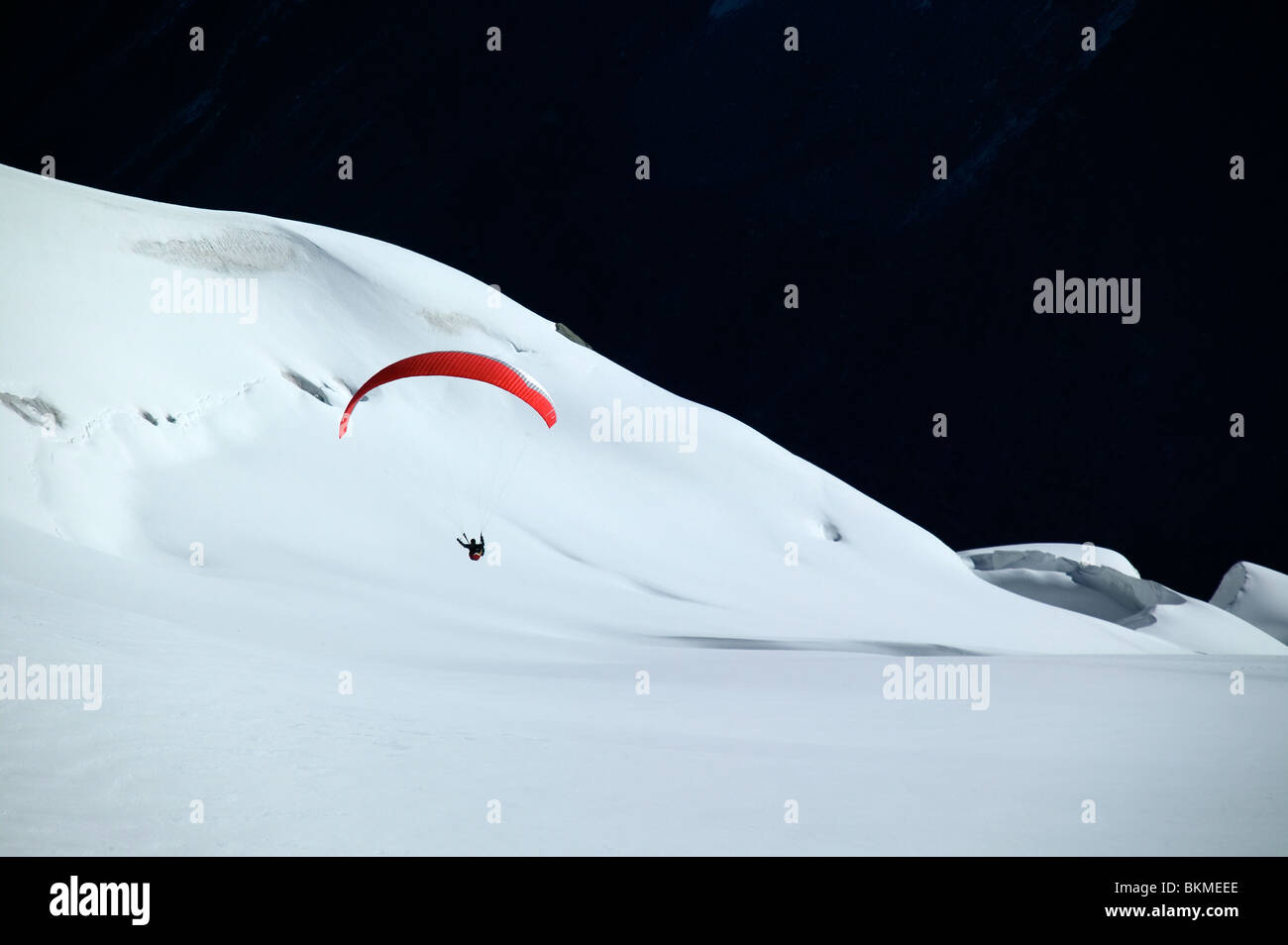 Hang glider coming in to land on snow covered mountain. Stock Photo