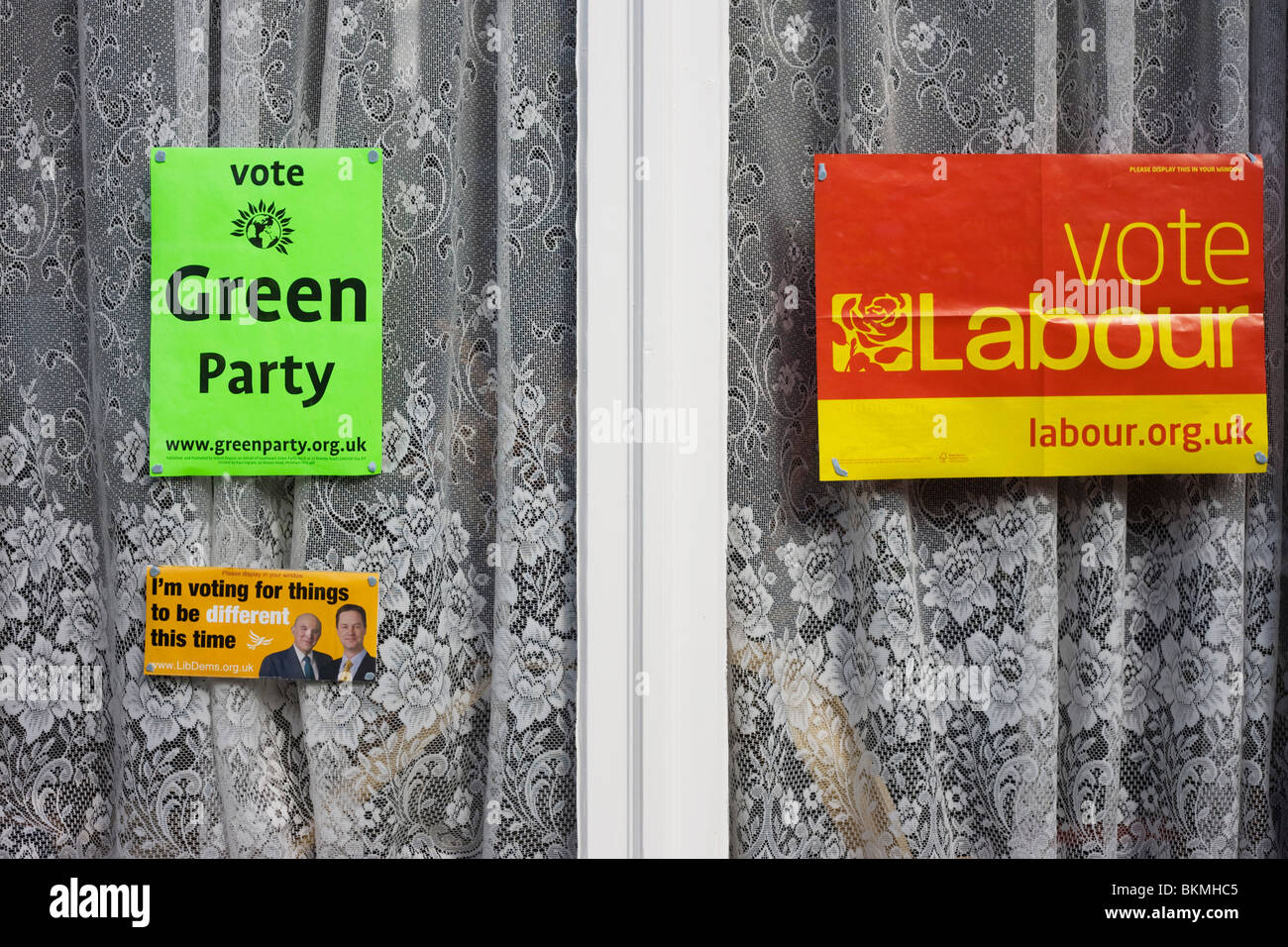 The three main British political parties: Greens, Labour and Conservatives are displayed in a south London home's front window. Stock Photo