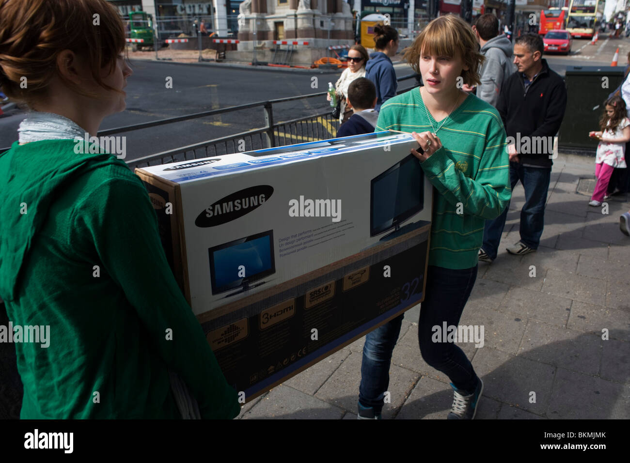 Two teenager consumers carry their new boxed Samsung flat screen TV through Brighton town centre. Stock Photo