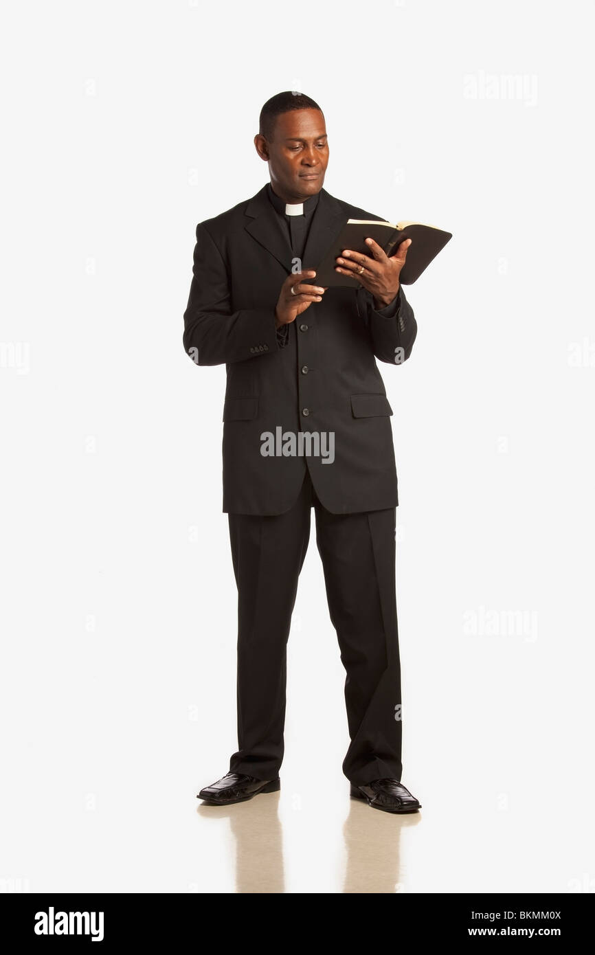 A Man Wearing A Clerical Collar And Reading From The Bible Stock Photo