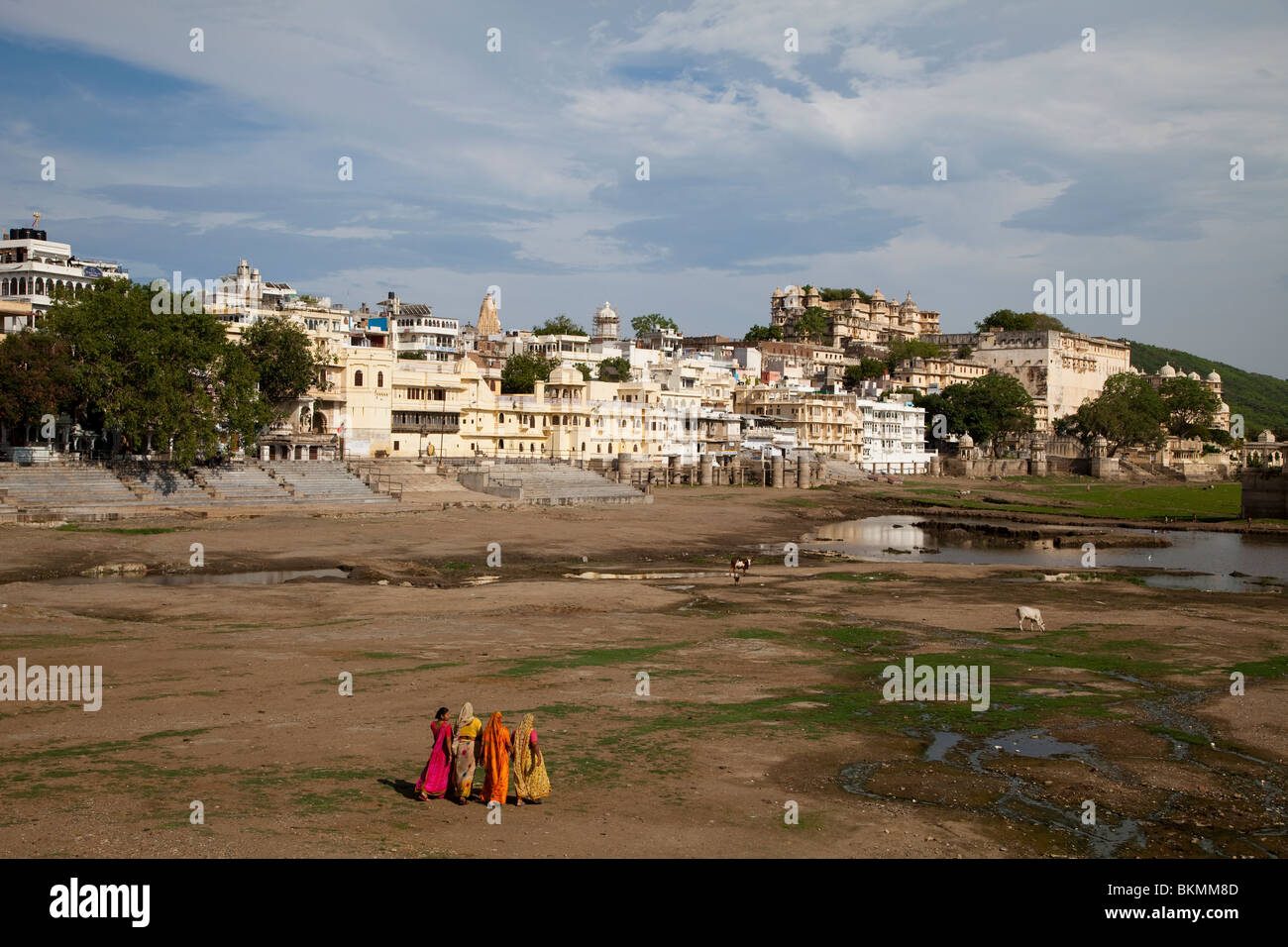 Women in saris walking across dried up lakebed, Udaipur, Rajasthan, India Stock Photo