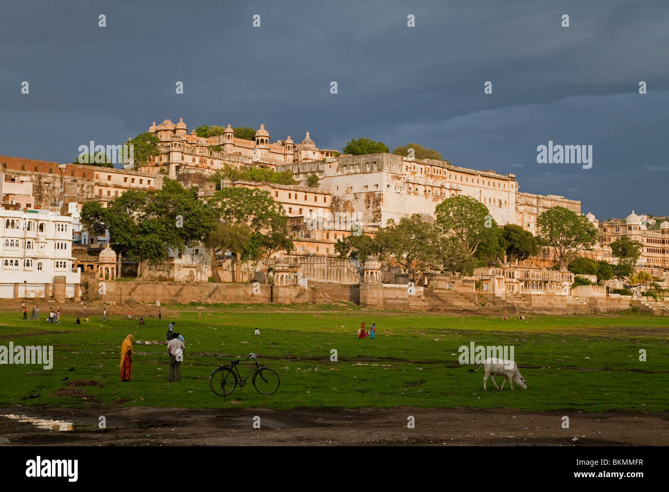 Dried up lake bed and view to City Palace with monsoon sky, Udaipur, India Stock Photo