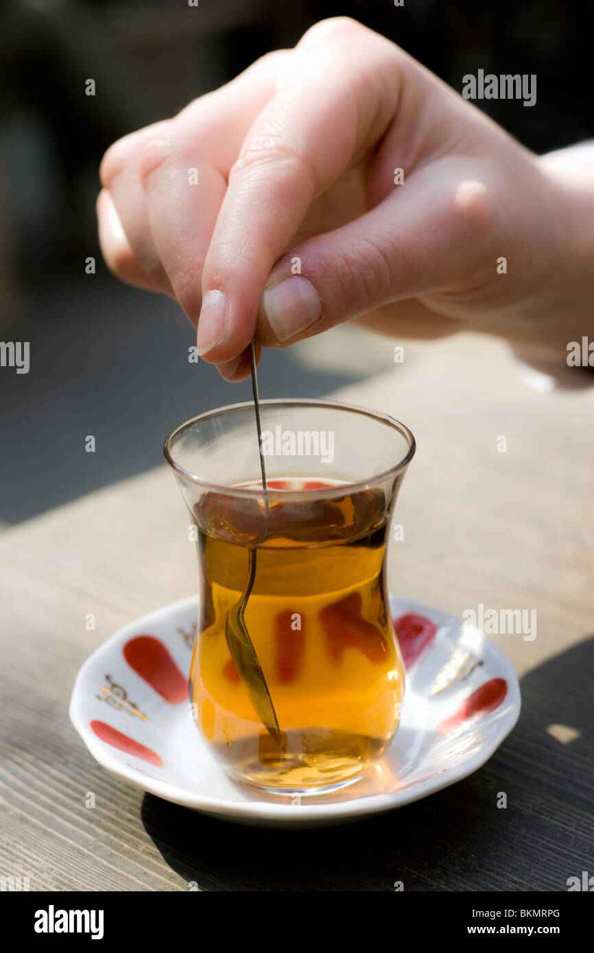Person stirring a glass of Apple Tea at a cafe in Istanbul, Turkey. Stock Photo