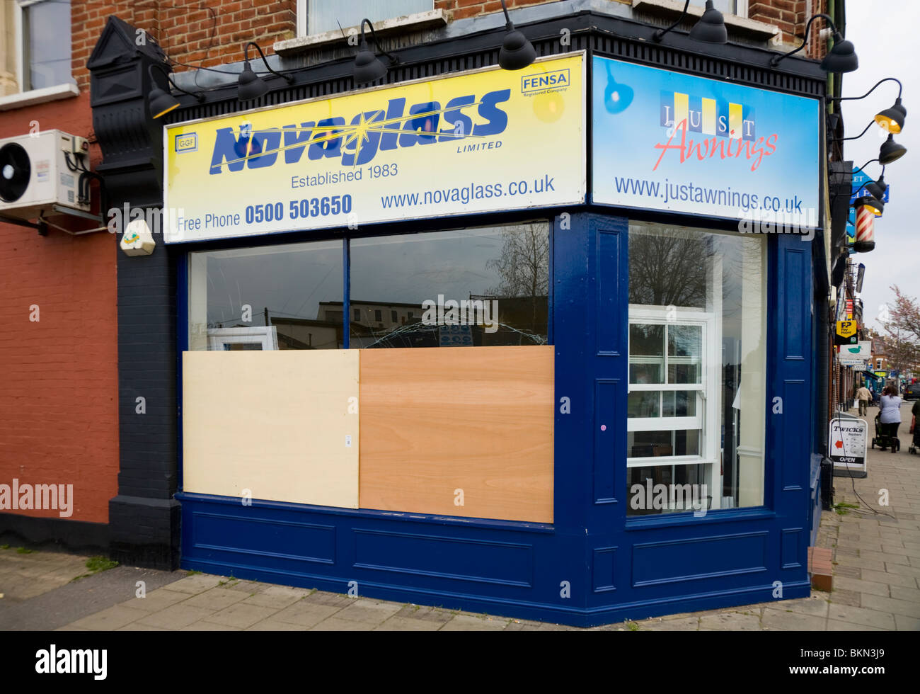 Glass shop window which has been broken by vandals and then been given a temporary repair / boarded up. Stock Photo