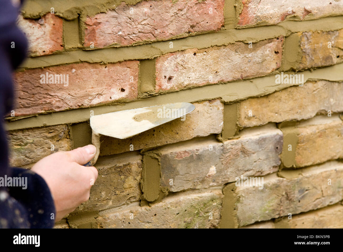 A brick wall being repointed / pointing a wall Stock Photo Alamy