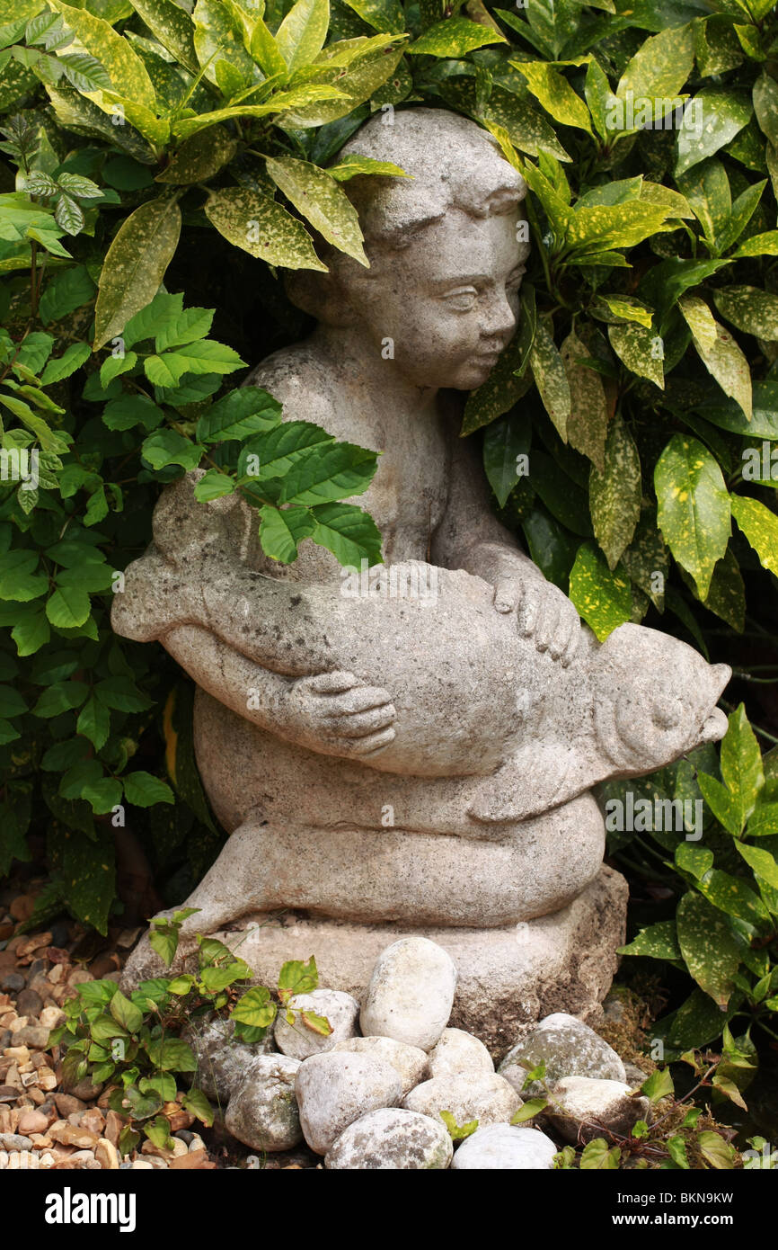 Beautiful garden stone statue, of a child and fish surrounded by plush