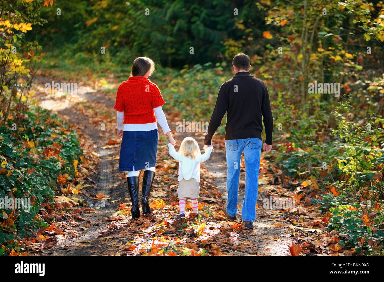 A Family Walking Down A Path In Autumn Stock Photo