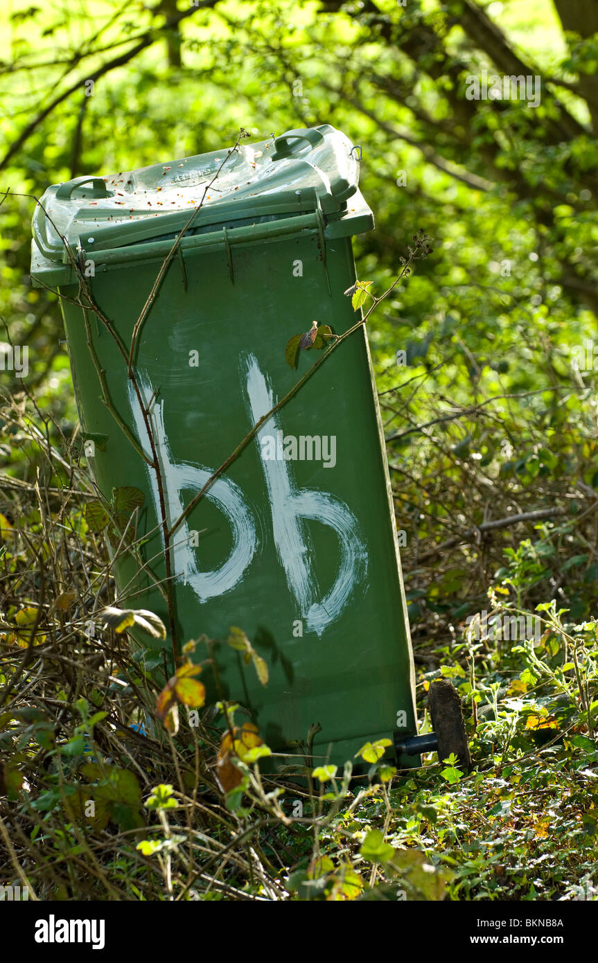 Discarded green plastic wheelie bin an eye sore in the countryside Stock Photo