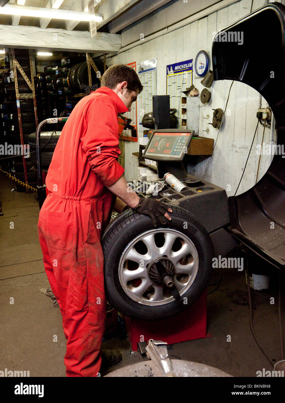 a garage worker balancing a wheel Stock Photo