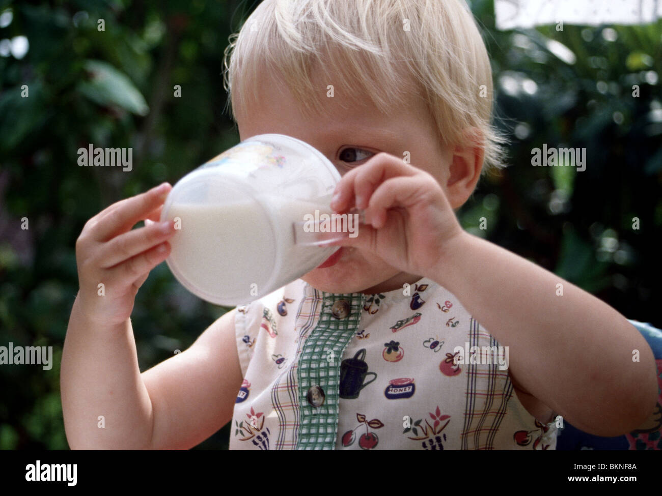 Toddler drinking milk from plastic mug Stock Photo Alamy