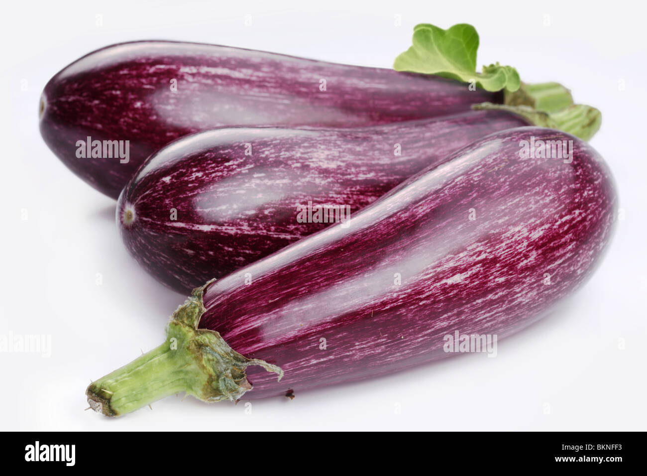 Purple eggplants with leaves on white background Stock Photo