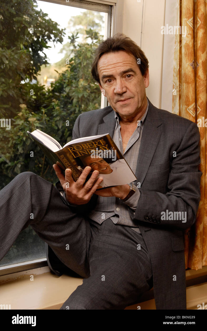 Actor Robert Lindsay reading by a window. He has a purpose built library in his home in Denham Bucks Stock Photo