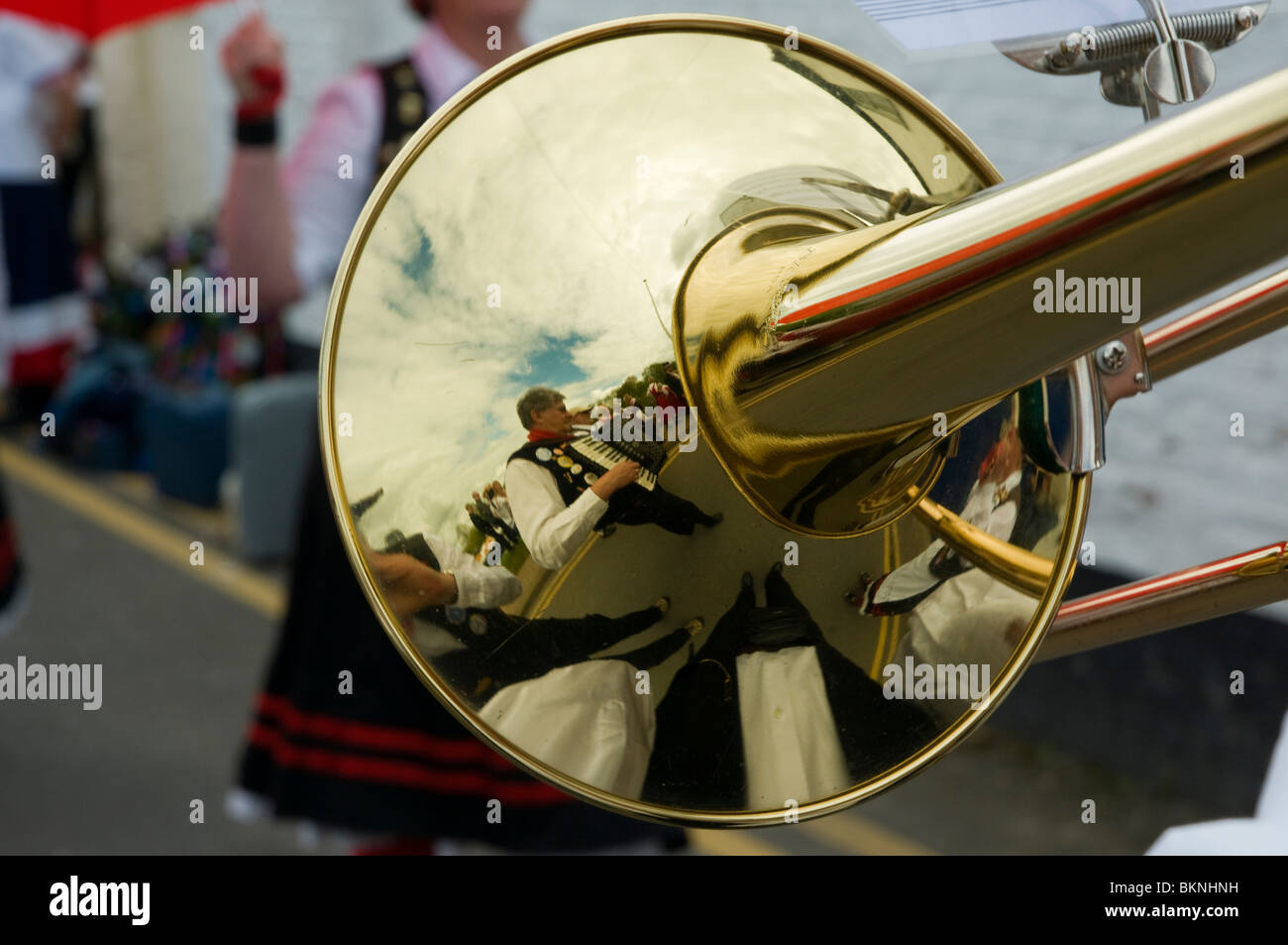 Accordionist reflected in the horn of a musician's trombone at the Upton Folk Festival, Stock Photo