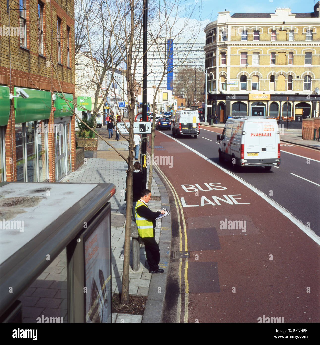 Traffic and bus inspector taking notes at a bus stop and bus lane, Camberwell, London England  KATHY DEWITT Stock Photo