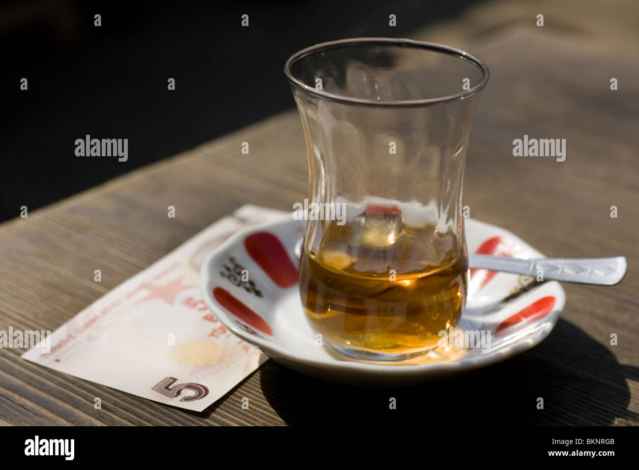 Almost empty glass of apple tea with 5 Turkish-Lire note left as payment. Stock Photo