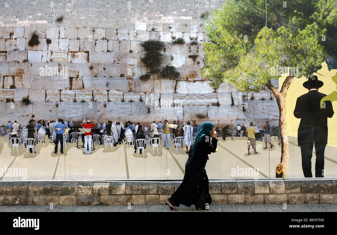 A muslim walks alongside a mural depicting the Wailing Wall in Jerusalem, Israel Stock Photo