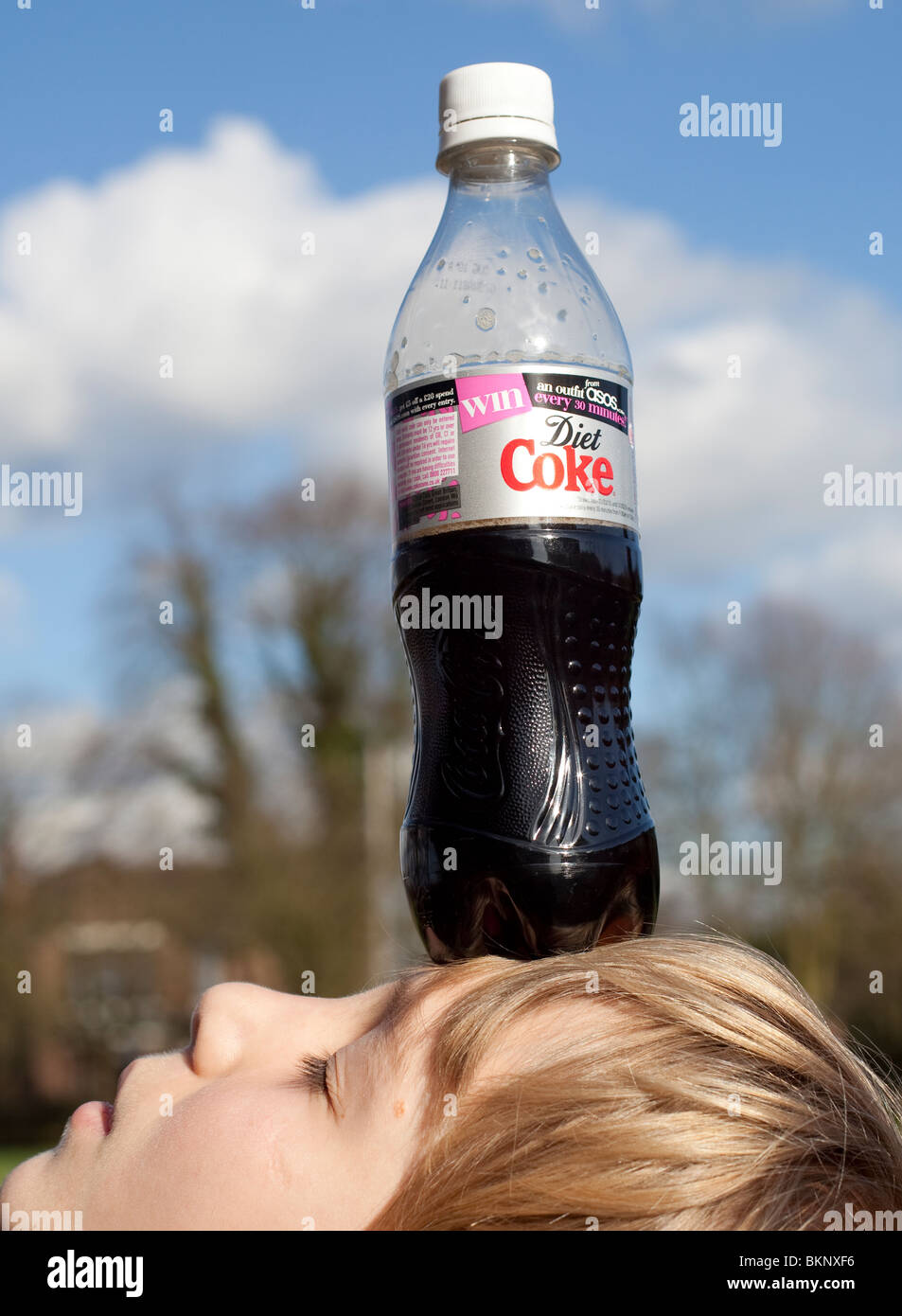 Boy balancing Coke bottle on head. Stock Photo