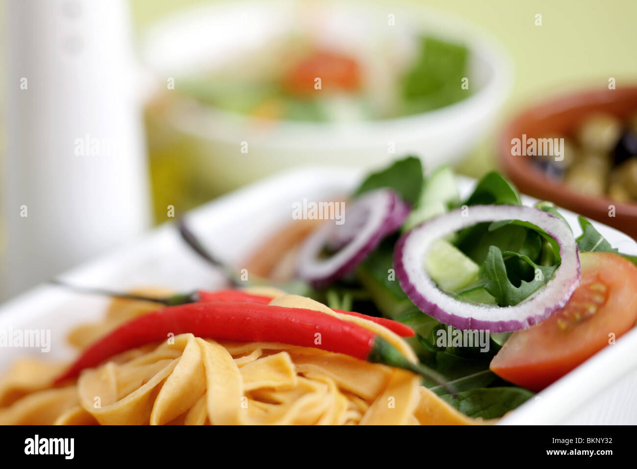 Authentic Italian Style Colourful Red Pepper and Chilli Tagliatelle Pasta Meal With A Salad And No People On A Table Top Setting Stock Photo