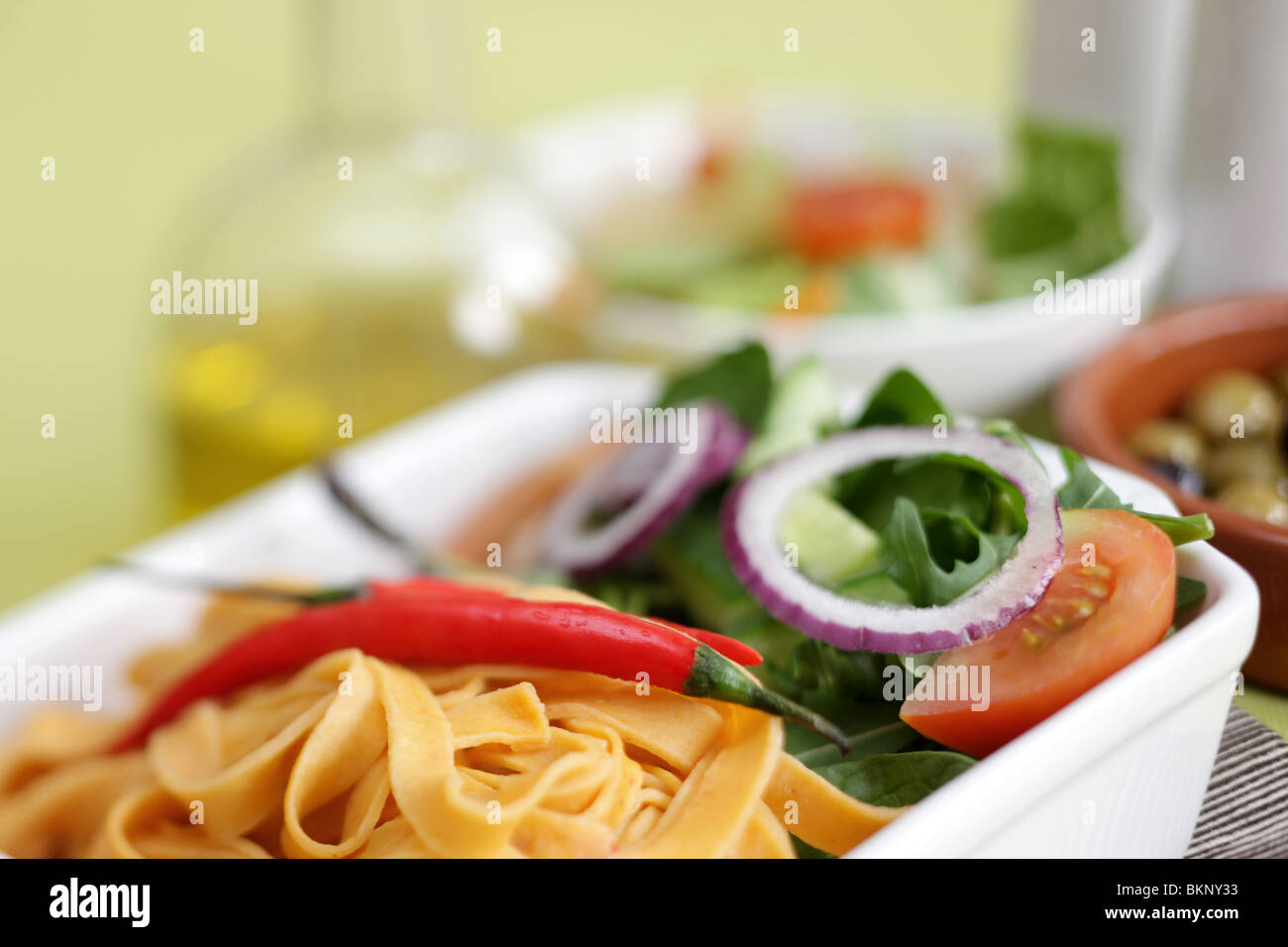 Authentic Italian Style Colourful Red Pepper and Chilli Tagliatelle Pasta Meal With A Salad And No People On A Table Top Setting Stock Photo