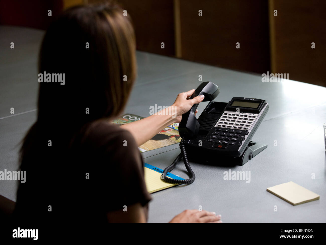 Woman picks up an office phone. Stock Photo