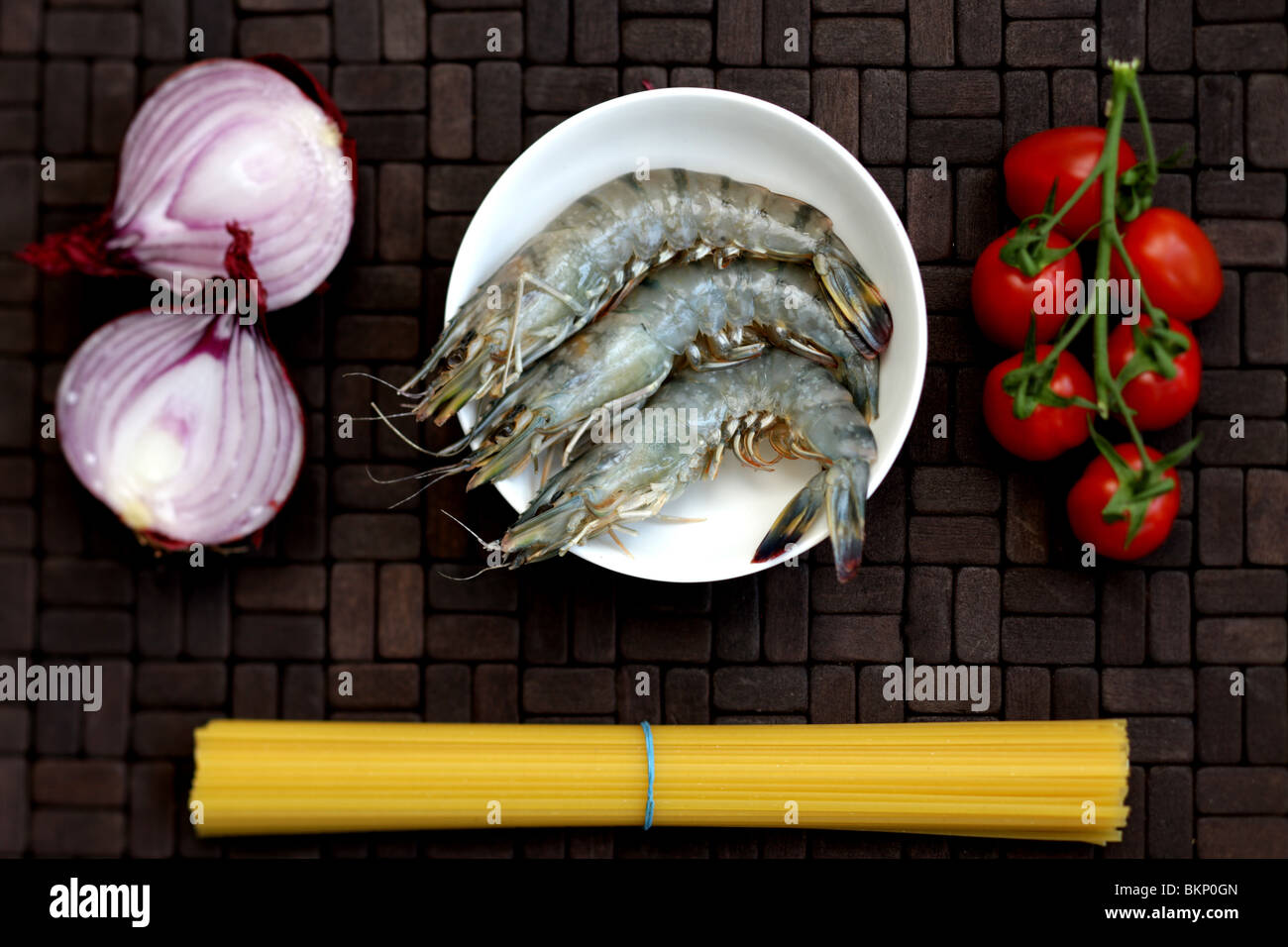 Uncooked Raw Fresh King Prawns With Linguine Pasta And Vine Tomatoes With No People On A Table Top Setting Stock Photo